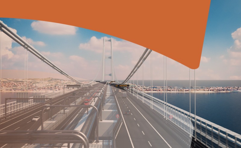 Aerial view of a suspension bridge over blue water, with multiple roadway lanes and a distant coastline beneath a partly cloudy sky, plus a large orange graphic at the top right corner (branding overlay).